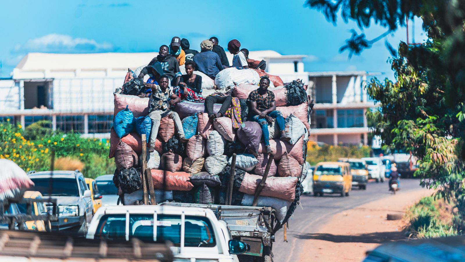 Passengers ride on top of a lorry stacked high with sacks of charcoal in traffic in Lubumbashi